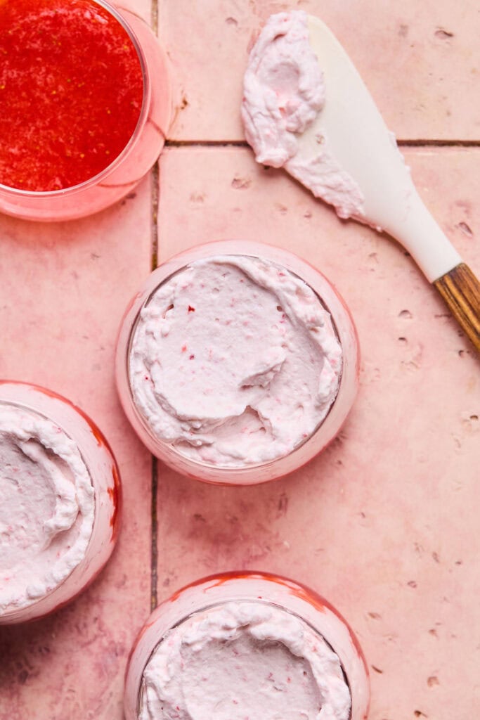 Strawberry cream mixture being added to small bowl with a spatula.