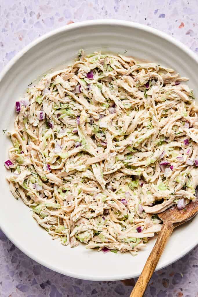 Tzatziki Chicken Salad in a bowl with a wooden spoon.