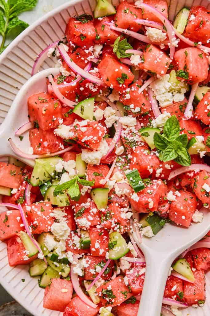 Zoomed in view of Watermelon Mint Salad in a alrge bowl with a wooden spoon.
