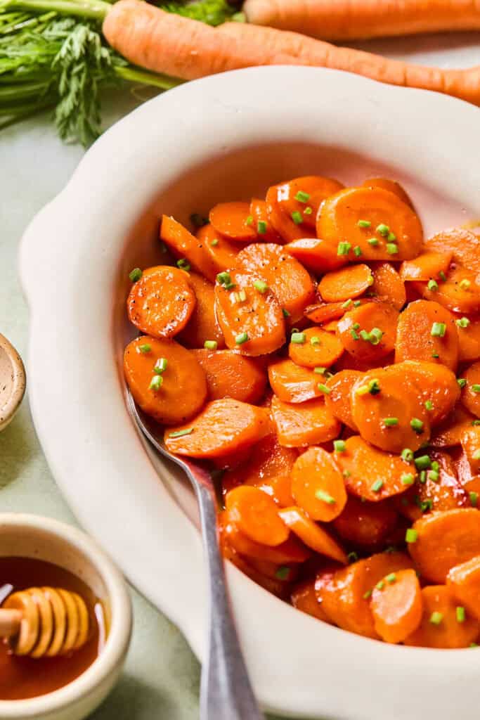 Honey Glazed Carrots in an oval serving dish with a spoon.