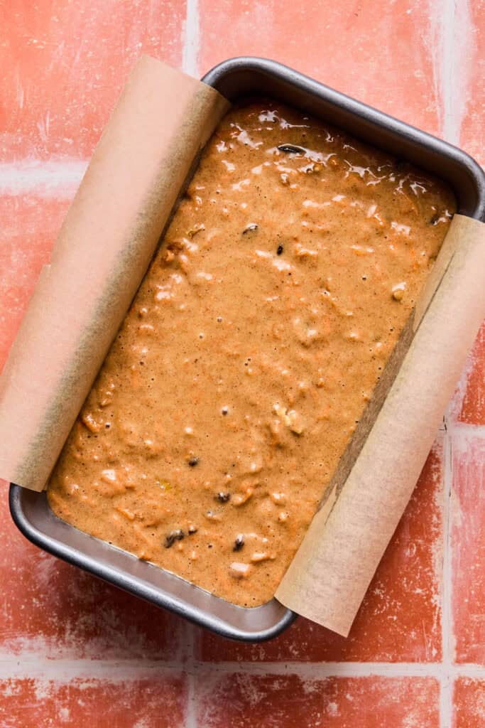 Carrot cake bread batter in a loaf pan with parchment paper.