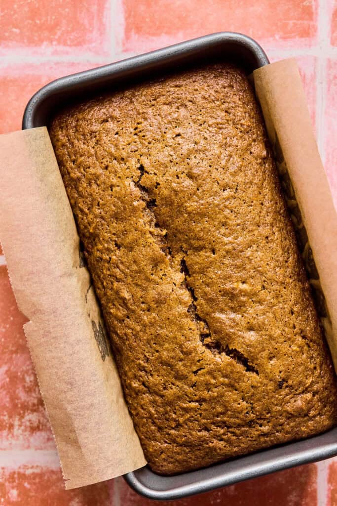 Carrot cake bread in a loaf pan with parchment paper.