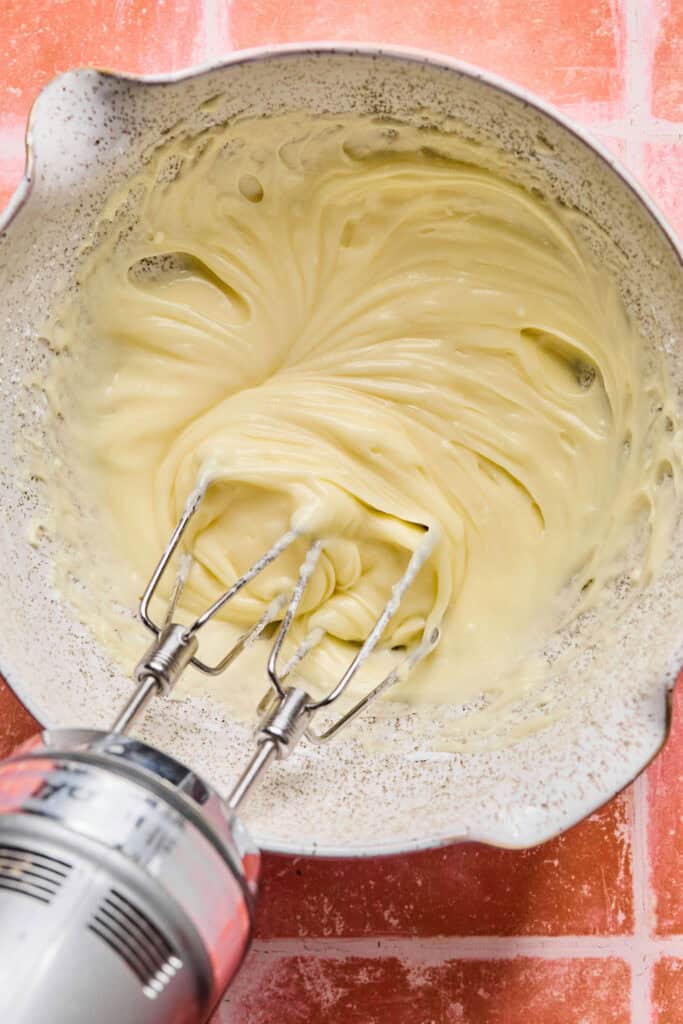 Cream cheese icing in a mixing bowl with an electric mixer.