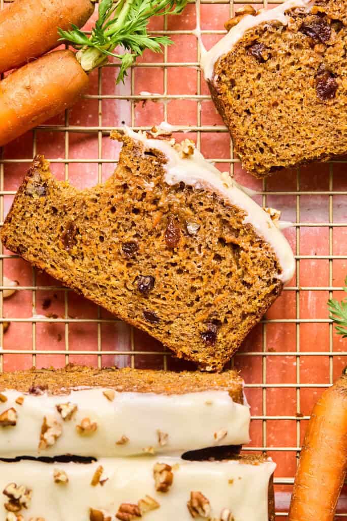 Slices of Carrot cake bread on a cooling rack garished with carrots.