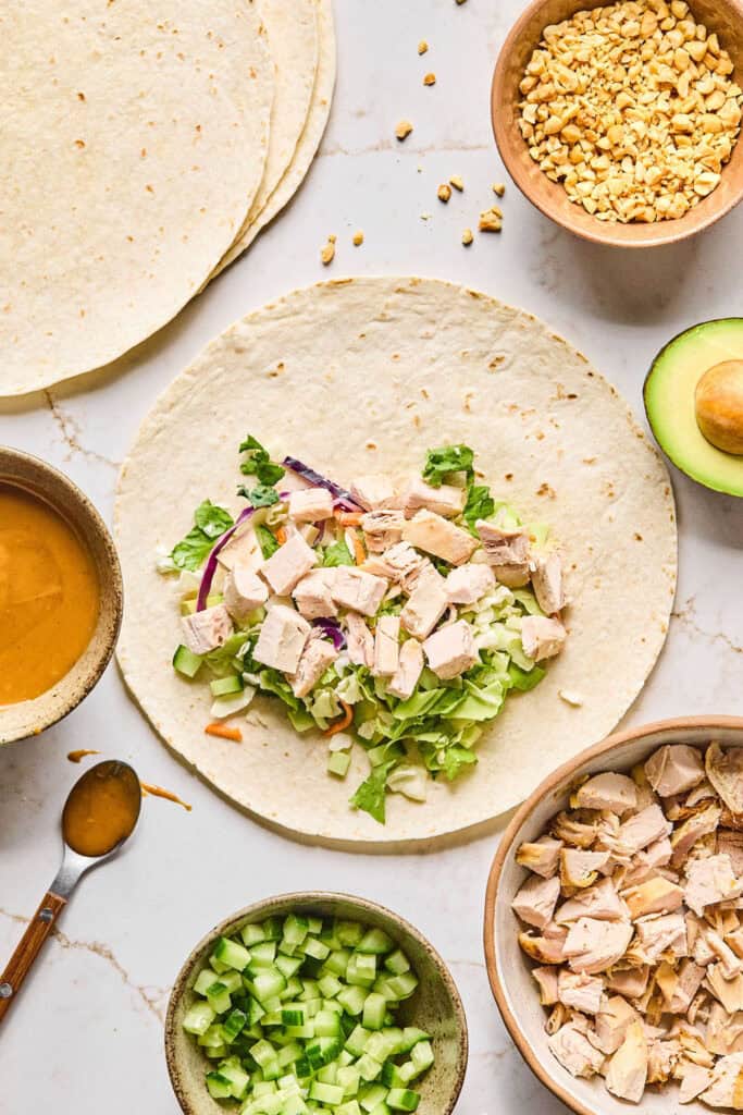 Other ingredient for Peanut chicken crunch wraps being added to the tortilla.