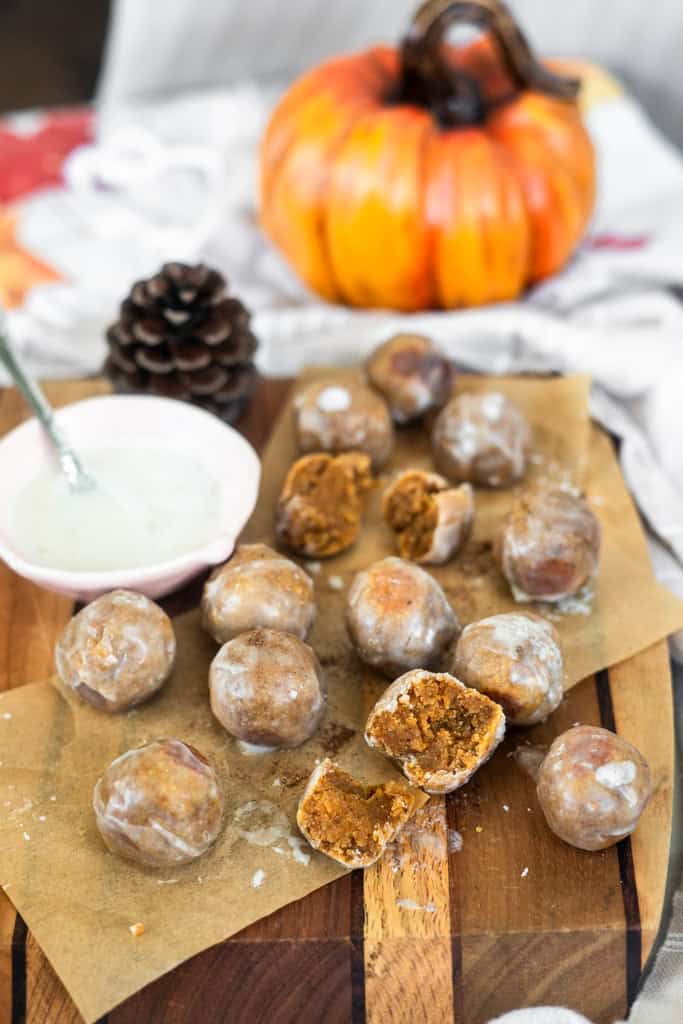 Pumpkin Spice Almond Flour Donut Holes on a cutting board with a side of glaze.
