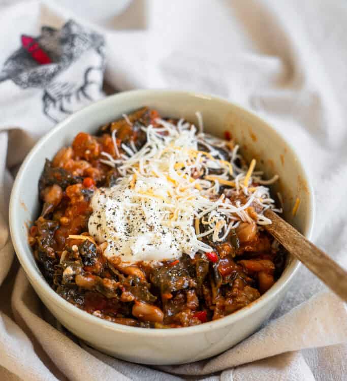 Spicy Sausage & Kale Chili in a bowl with a spoon.