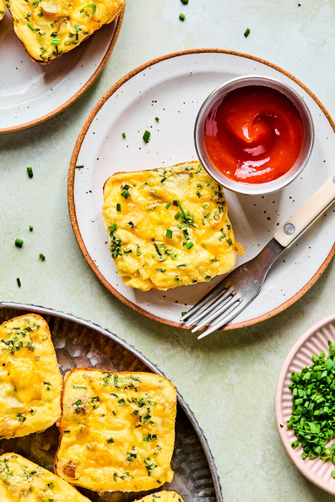 Cheesy Potato Chive Egg Bite on a small plate with a fork and side of ketchup.