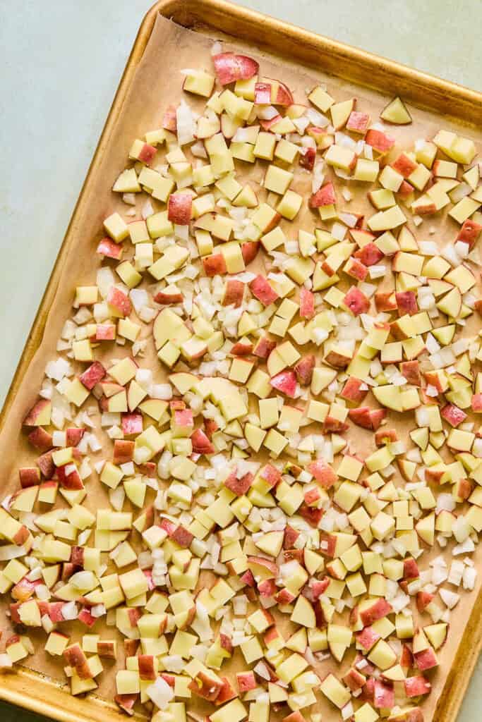 Diced potatoes and onions on a baking sheet.