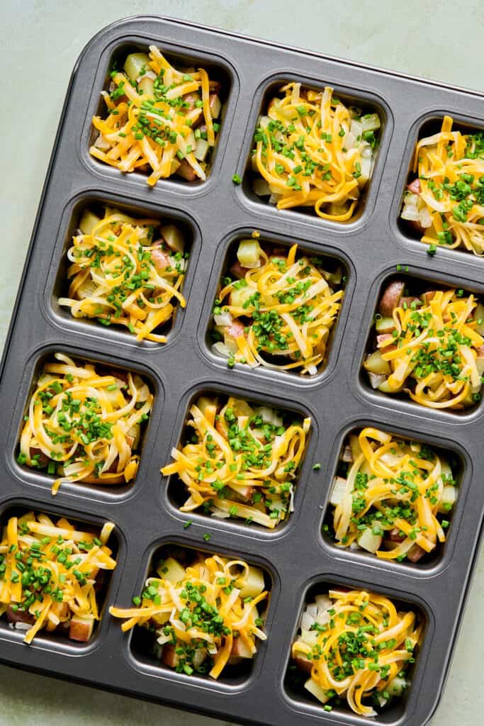 Shredded cheese and chives added to the potatoes in the brownie pan.