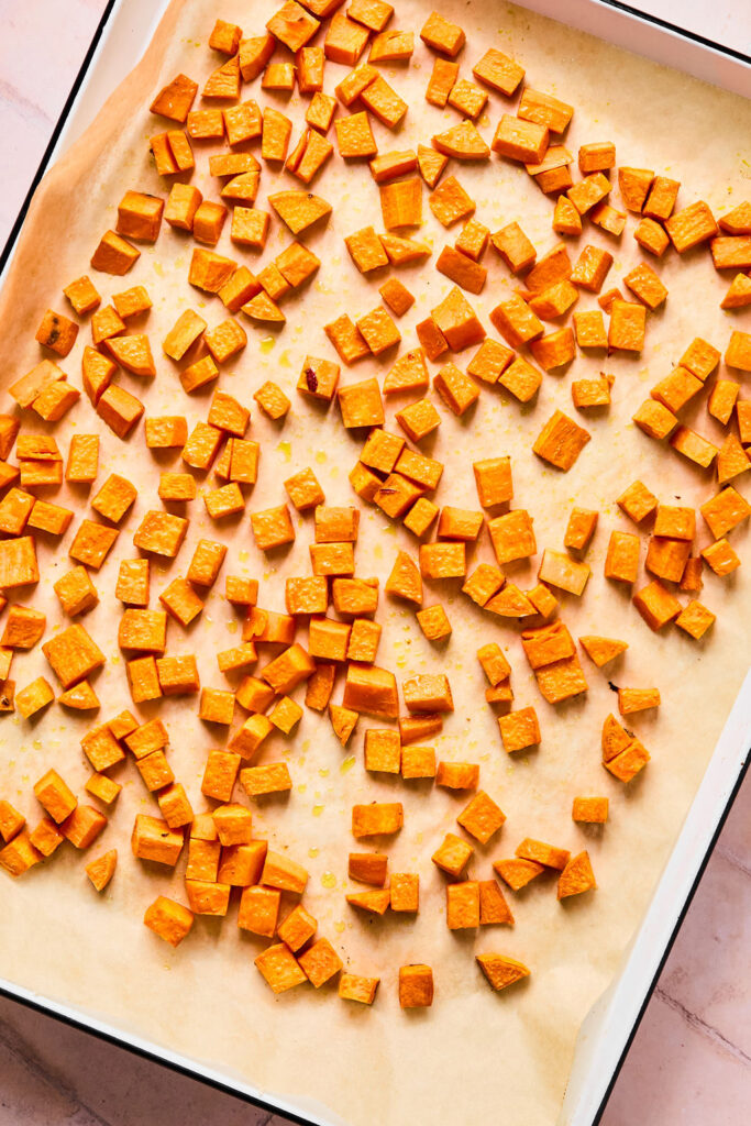 Cubed sweet potatoes on a baking sheet with parchment  paper.