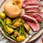 Sheet Pan Steak and Potatoes sheet plan on a plate with a roll.