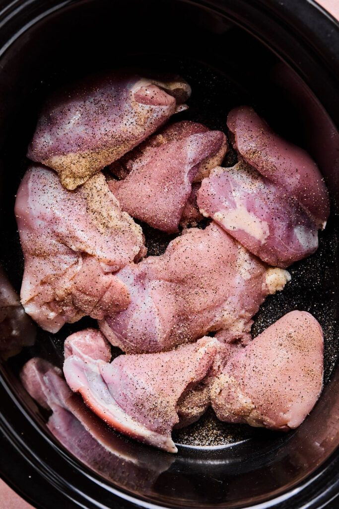 Raw chicken thighs in a crock pot.