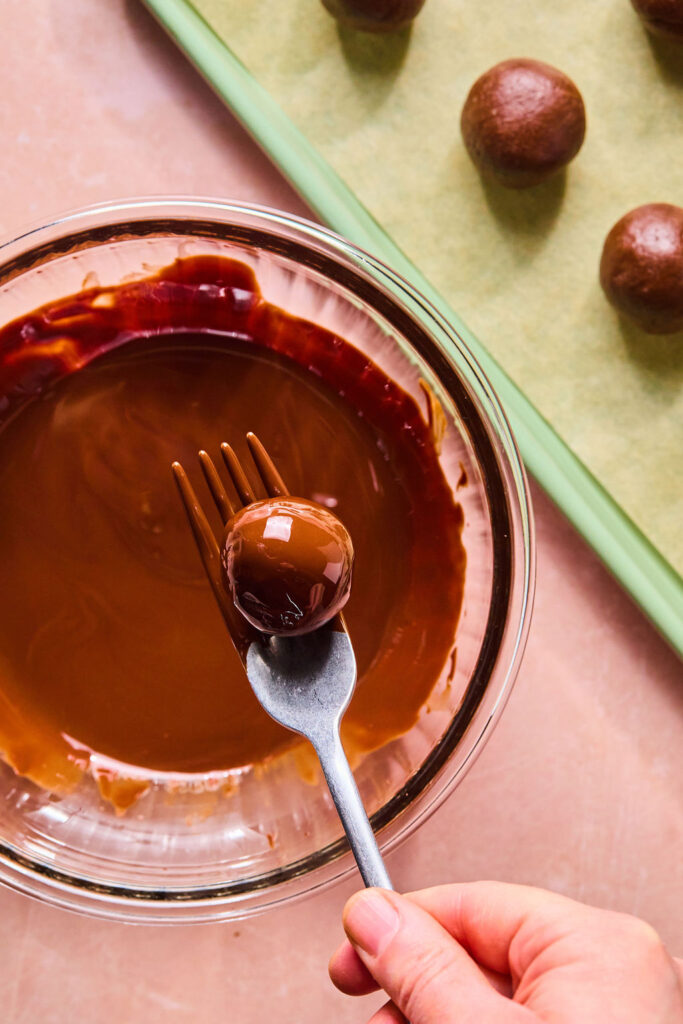Cosmic Brownie Protein Bite being dipped in melted chocolate with a fork.