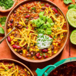 High Fiber Quinoa Chili in bowls topped with shredded cheese, avocado, and sour cream.
