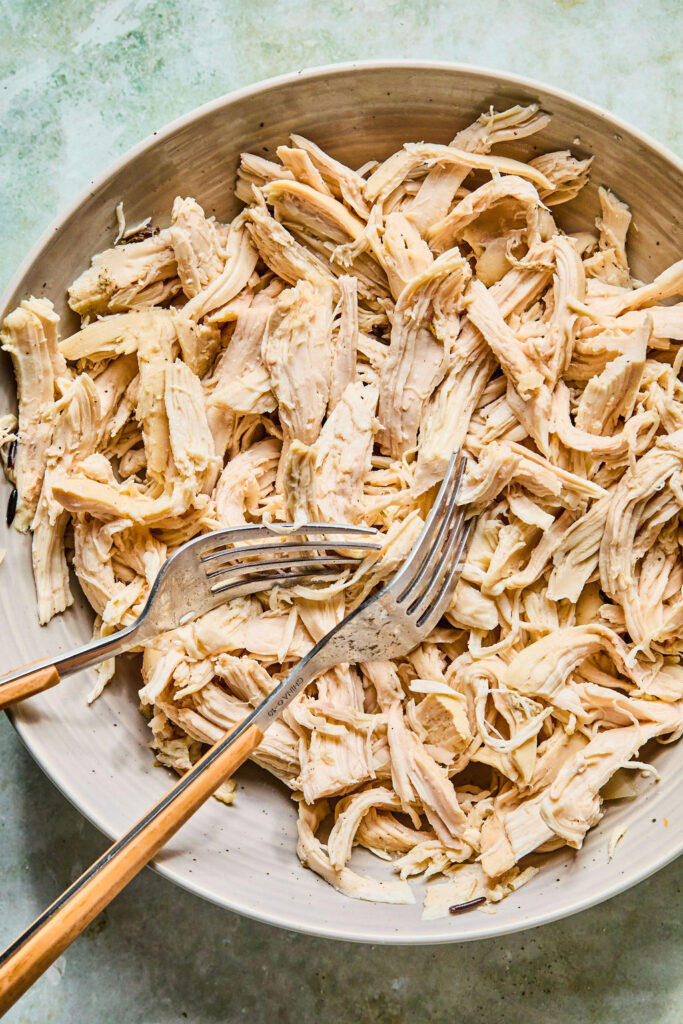 Shredded chicken in a bowl with a 2 forks.