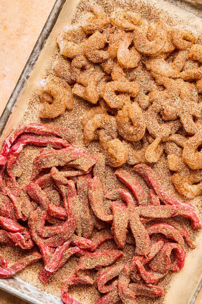 Raw steak and shrimp covered with spices.