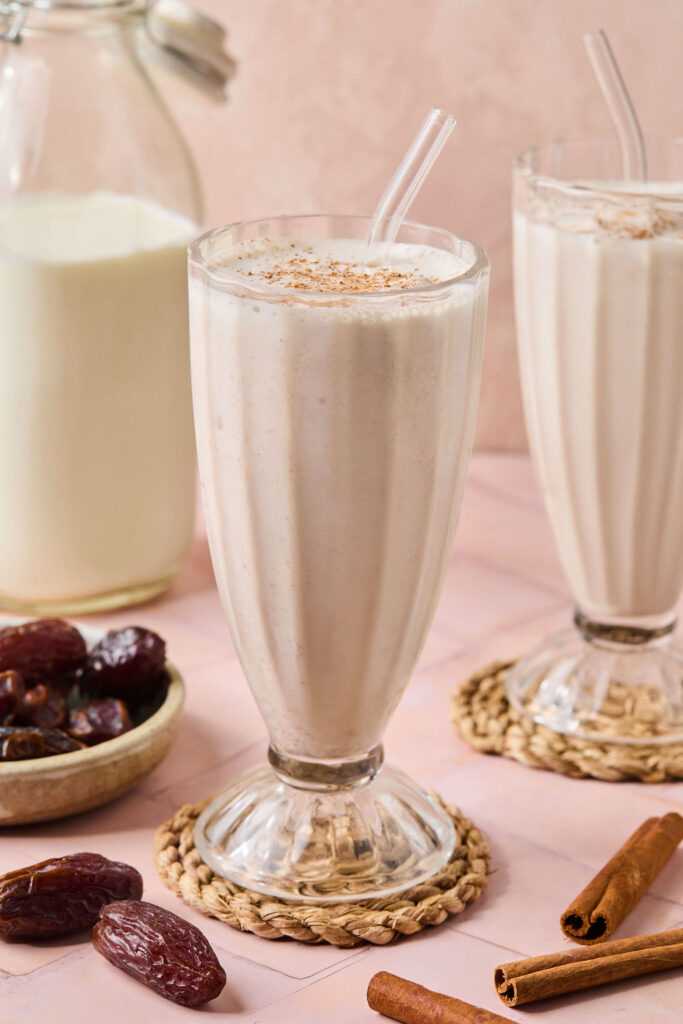 Cinnamon Vanilla Date Milkshake in a glass with a straw.