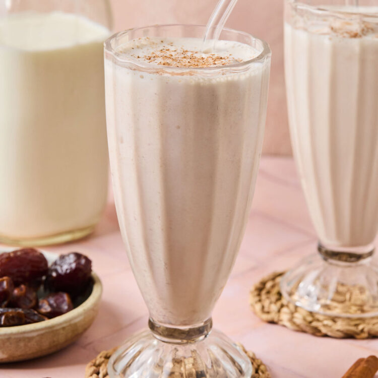 Cinnamon Vanilla Date Milkshake in a glass with a straw.