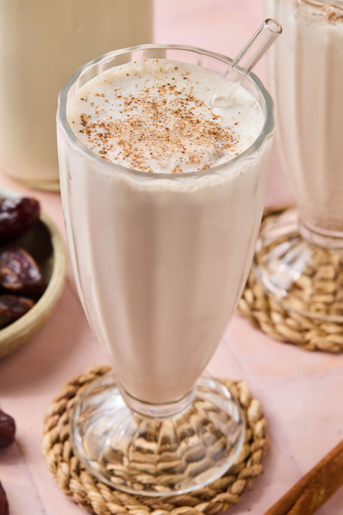 Cinnamon Vanilla Date Milkshake in s glass with a straw.