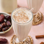 Cinnamon Vanilla Date Milkshake in a glass with a straw.