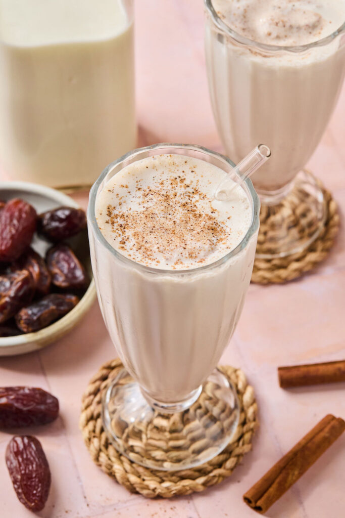 Cinnamon Vanilla Date Milkshake in a glass with a straw.