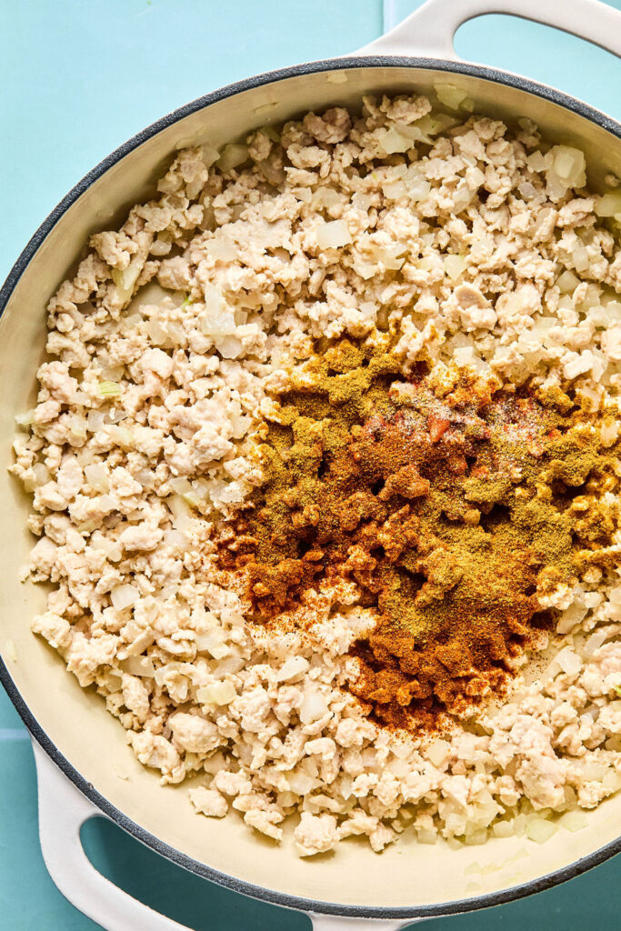Cooked turkey ground turkey with seasonings in a skillet.