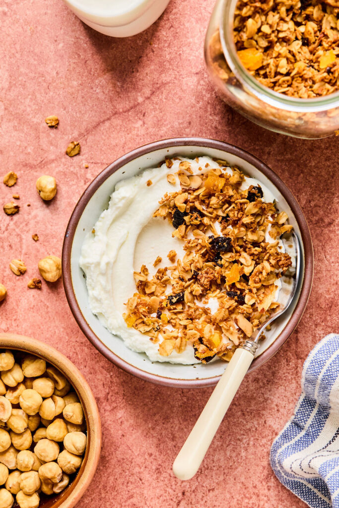 Yogurt topped with Hazelnut Maple Granola in bowls with spoons.