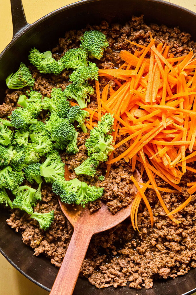 Chopped broccolli and shredded carrots in a skillet.