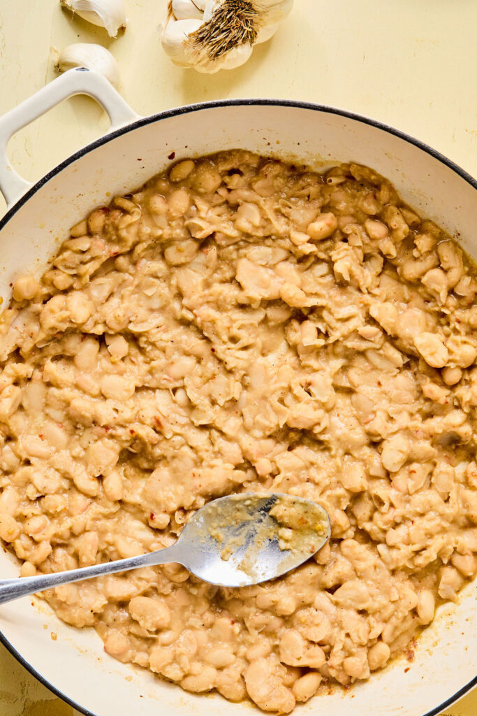 Beans being smashed with the back of a spoon.