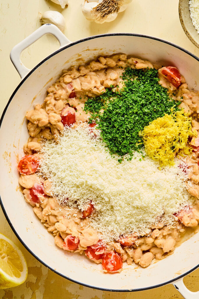 Parmesan, Pecorino, lemon juice, lemon zest, and fresh herbs add on top of the white beans.