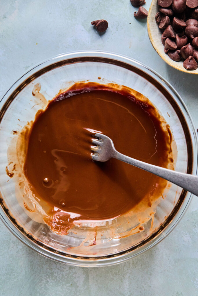 Metled chocolate and coconut oil in a bowl with a fork.