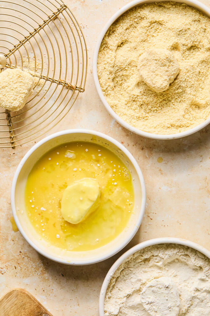 Bowls of flour, butter, and cracker crumbs with slices of goat cheese.