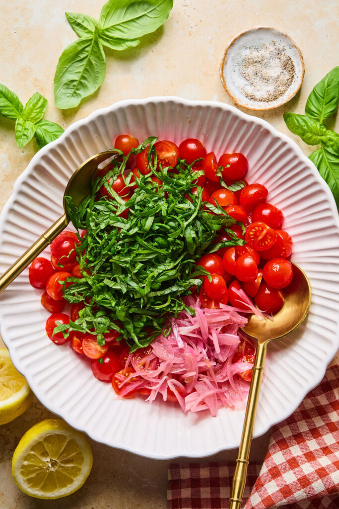 Vegetables for Crispy Goat Cheese & Tomato Salad recipe in a bowl with a spoon.