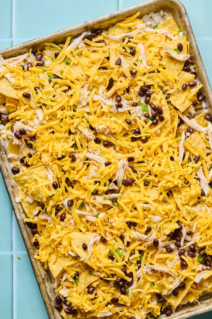 Shredded cheese added to the top of the chicken sheet pan nachos.