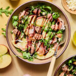 Proscuitto Apple Arugula Salad in a bowl drizzled with balsamic glaze.