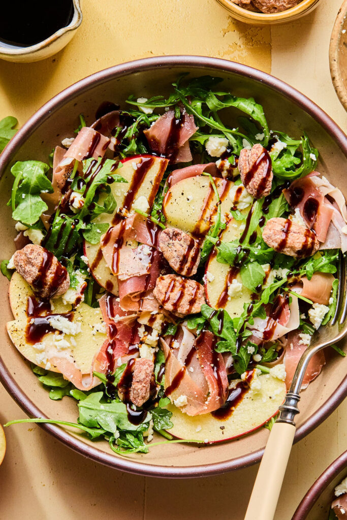 Proscuitto Apple Arugula Salad in a bowl with a fork.