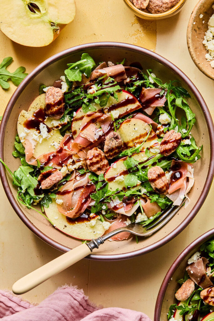Proscuitto Apple Arugula Salad in a bowl with a fork.