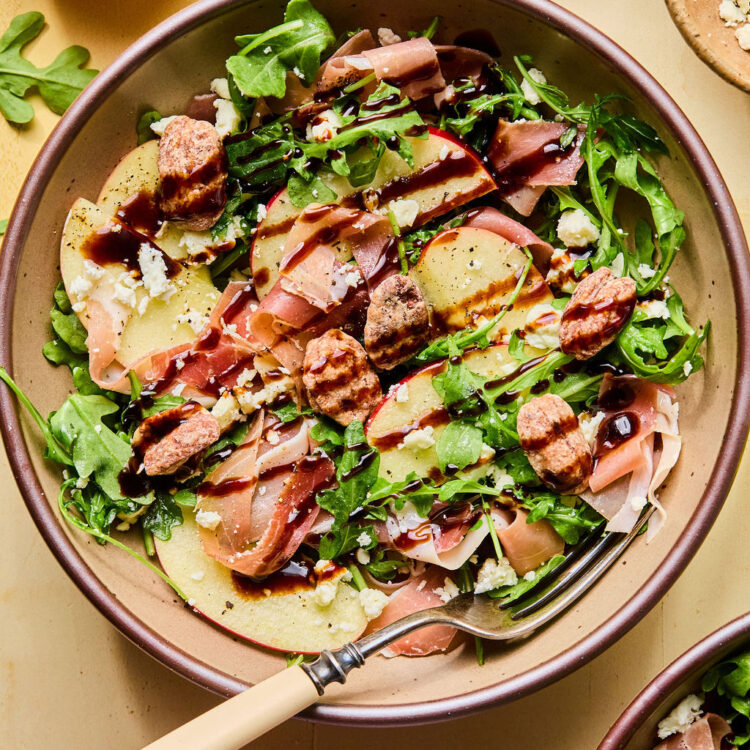 Proscuitto Apple Arugula Salad in a bowl with a fork.