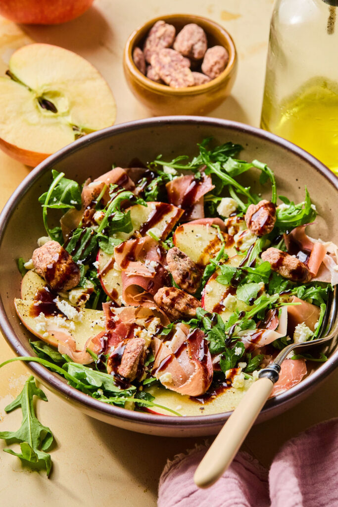 Proscuitto Apple Arugula Salad in a bowl with a fork.