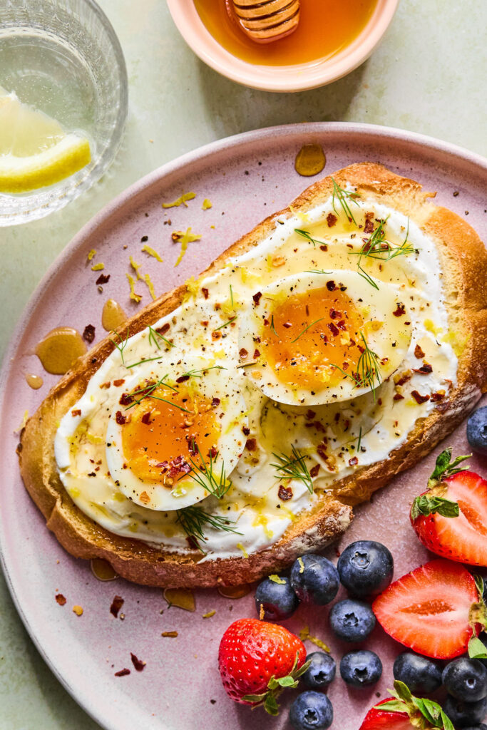 Hot Honey Cottage Cheese Toast with Eggs on a plate with a side of berries.