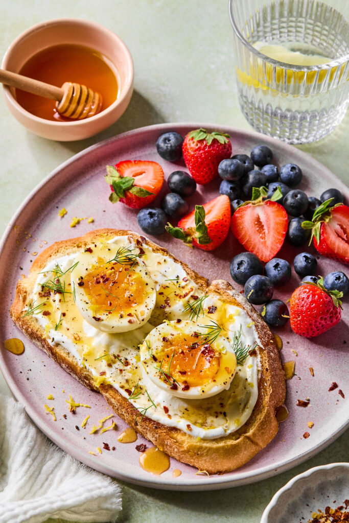 Hot Honey Cottage Cheese Toast with Eggs on a plate with a side of berries.