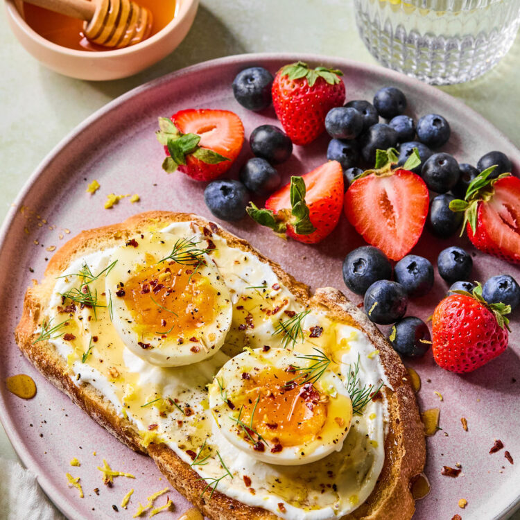 Hot Honey Cottage Cheese Toast with Eggs on a plate with a side of berries.