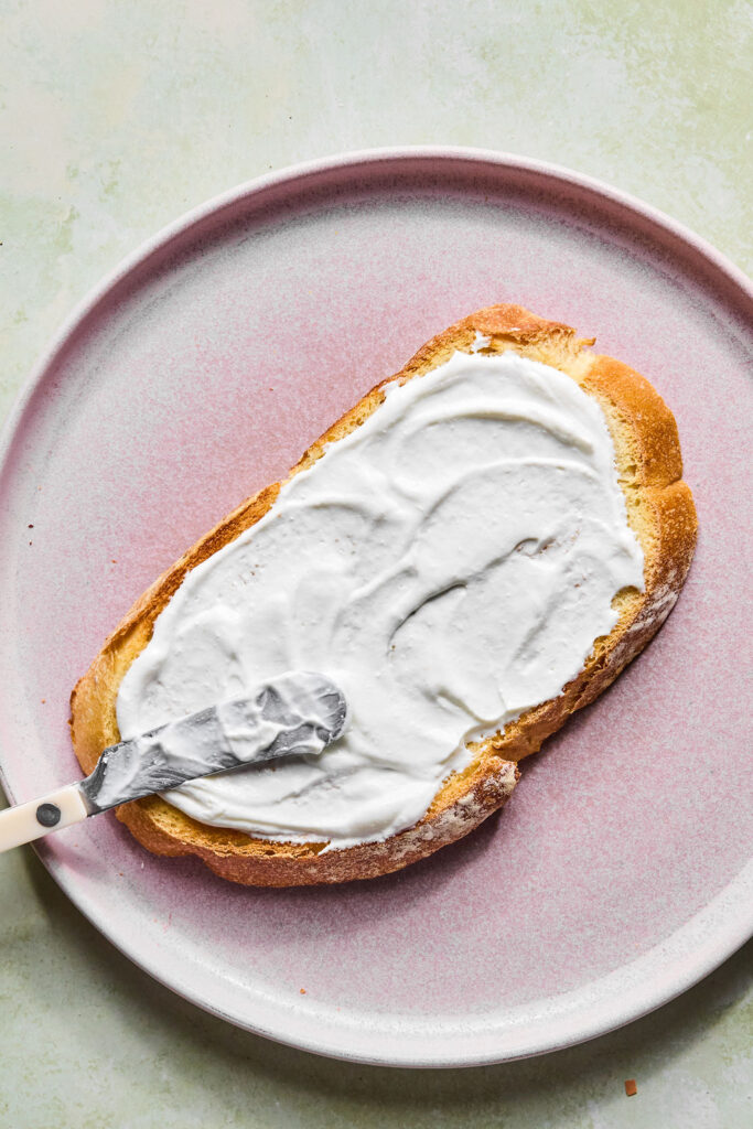 Cottage cheese mixture being spread on a slice of bread.