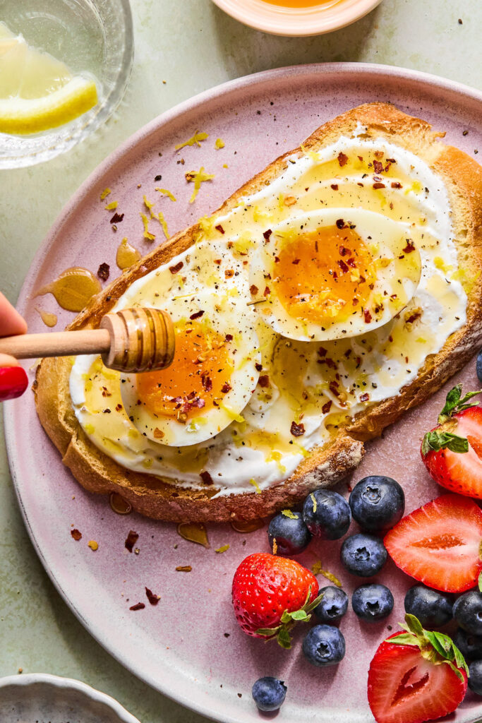 Hot Honey Cottage Cheese Toast with Eggs being drizzled with hot honey.