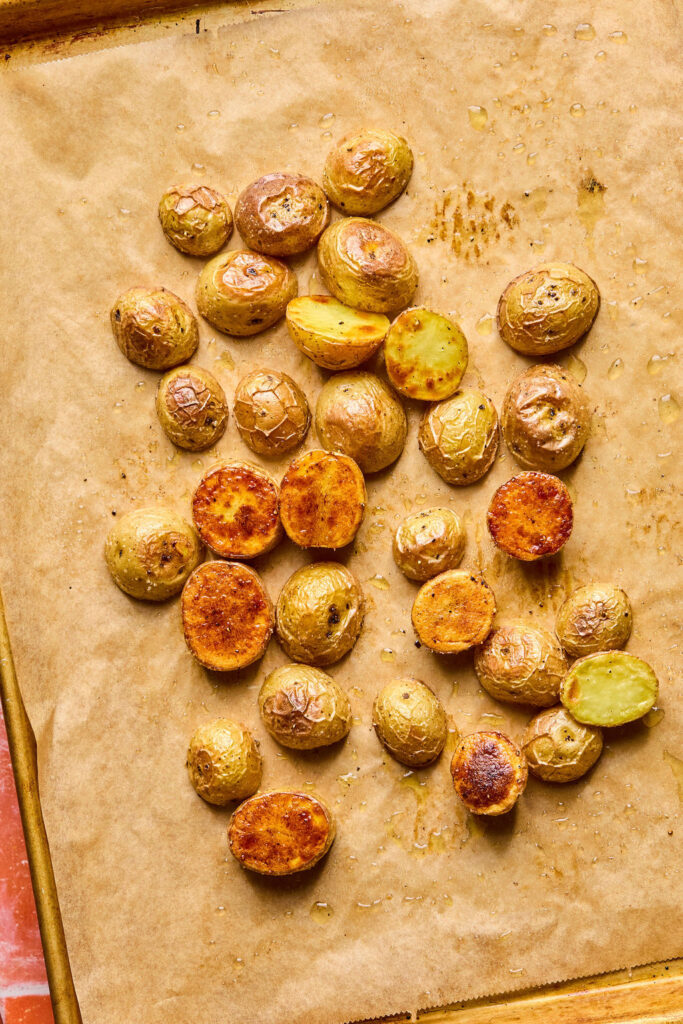 Baby potatoes cut in half on a baking sheet after being baked. 