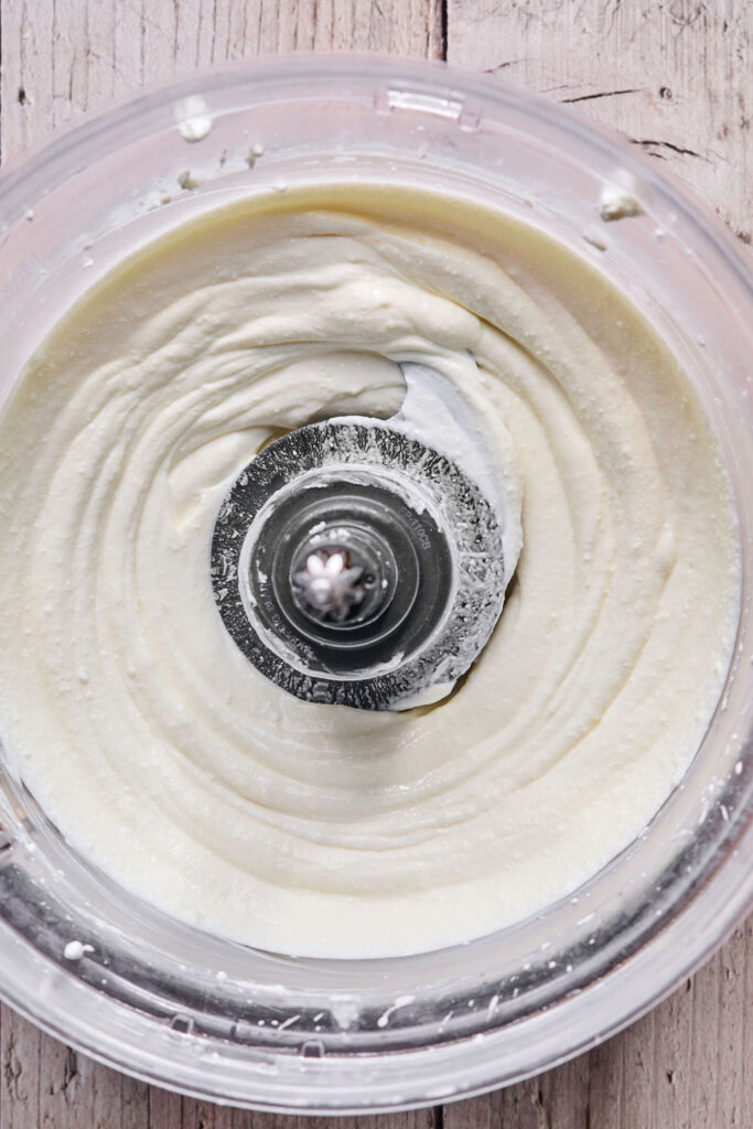 Cottage cheese and cream cheese mixture in a food processor bowl.