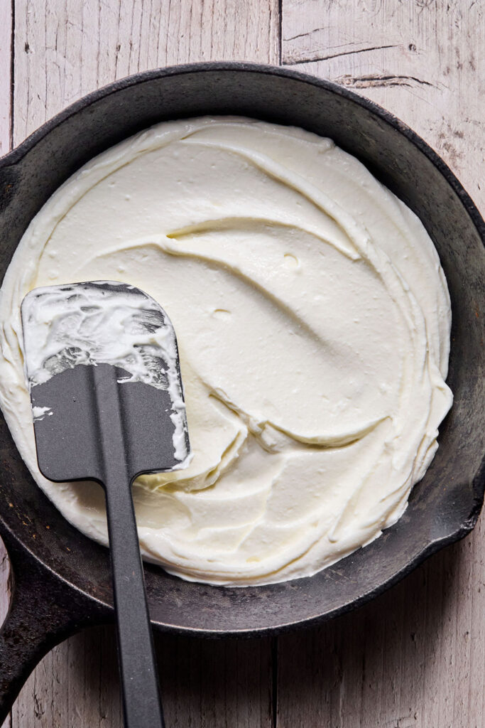 Cheese mixture being spread in a round dish.