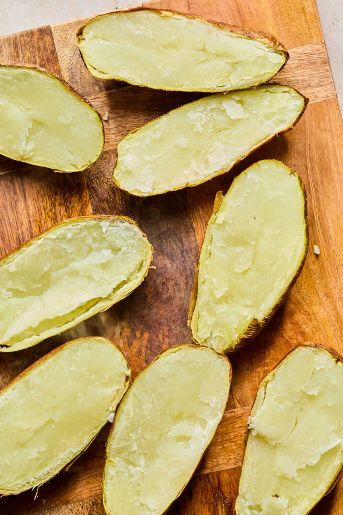 Halved potatoes face up on a cutting board.