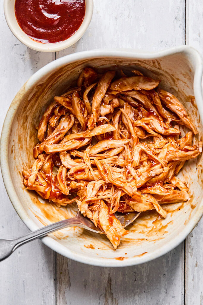Shredded BBQ chicken in a bowl with a fork.